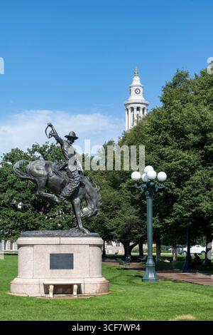 Denver, CO, USA, 11. Juni 2025; Bronco Buster-Statue im Civic Center Park mit Uhrenturm des Stadtrates von Denver im Hintergrund Stockfoto