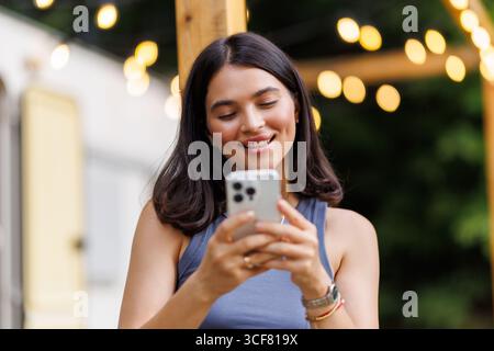 Die junge hübsche Frau benutzt das Telefon vor dem gemieteten Wohnmobil Stockfoto