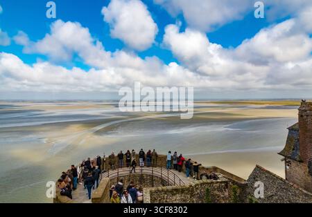 Im Vordergrund treffen sich die Besucher auf dem Nordturm (Tour du Nord), einem runden mittelalterlichen Wachturm auf einem Felsvorsprung entlang des Mont-Saint-Michel... Stockfoto