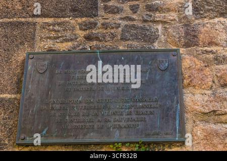 Großartige Nahaufnahme der Gedenktafel zum UNESCO-Weltkulturerbe von Mont-Saint-Michel, eine Markierung, die an der befestigten Mauer im ersten Innenhof neben dem... Stockfoto