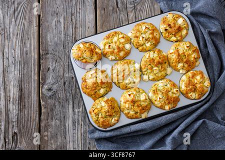 Zucchini Feta Muffins in Muffindose auf rustikalem Holztisch mit Küchentuch, horizontaler Blick von oben, nicht AI generiert, flache Lage, freier Platz Stockfoto