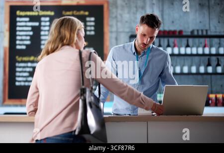 Frau, Die Kreditkarte Benutzt, Um Kaffee In Der Ladenkasse Zu Kaufen. Mögliche Berufe: Barista, Inhaber Kleiner Unternehmen Stockfoto