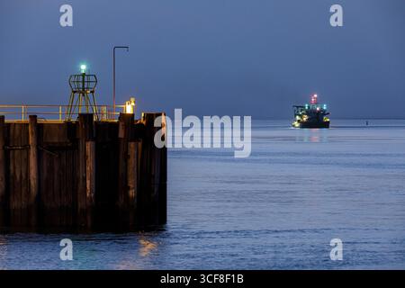 Hafeneingang in Cuxhaven an der Elbmündung bei Nacht, im Schifffahrtskanal ein Bagger während seiner Arbeit, Cuxhaven, Bremen, Deutschland Stockfoto