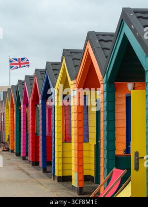 Eine Reihe von bunten traditionellen Strandhütten an der Promenade im beliebten Badeort Saltburn-by-the-Sea, North Yorkshire, Großbritannien. Stockfoto