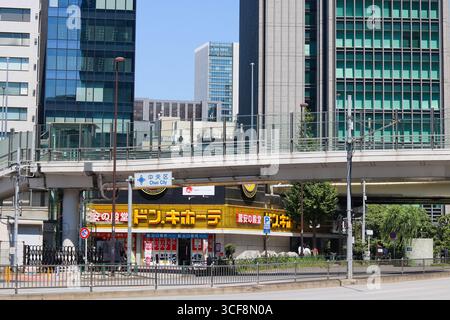 TOKIO, JAPAN - 19. August 2025: Hauptstraße mit Don Quijote-Geschäft und apedestrischer Fußgängerbrücke. Es ist in Shimbashi an der Grenze zwischen Chuo und Minato Wards. Stockfoto