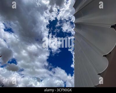 Geometrische, moderne Gebäudefassade, die sich in Pescara, Italien, nach oben erhebt und ein architektonisches Muster vor wolkenblauem Hintergrund enthüllt Stockfoto