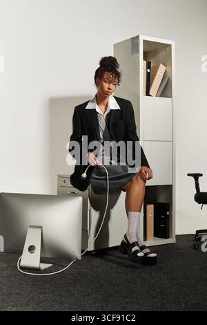 Stilvoll gekleidet verbindet die junge Frau die Ausrüstung elegant im Sitzen. Stockfoto