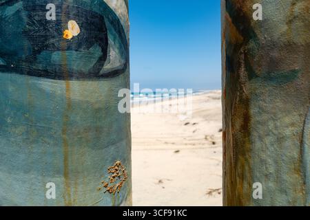 Blaues Auge auf lackierten Grenzmauern aus Metall-Barpfosten mit Blick von den Stränden von Playas de Tijuana bis zum San Diego County. Stockfoto