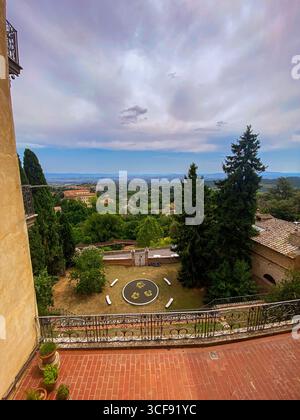 Panoramablick von einem Balkon mit Blick auf einen Garten und die sanften Hügel des Val d'Orcia in Montepulciano, Toskana, Italien, unter bewölktem Himmel Stockfoto