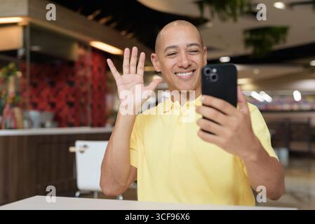 Porträt eines Reifen italienischen Mannes, der drinnen in einem modernen Restaurant sitzt und das Telefon aus der Ferne arbeitet Stockfoto