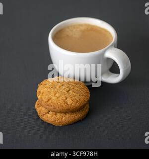 Ein Espresso-Shot-Kaffee mit cremigem Schaum und zwei Haferkeksen auf dunklem Tisch, gemütliche und einladende Snackszene, perfekt für eine entspannende Pause oder einen morgendlichen Genuss Stockfoto