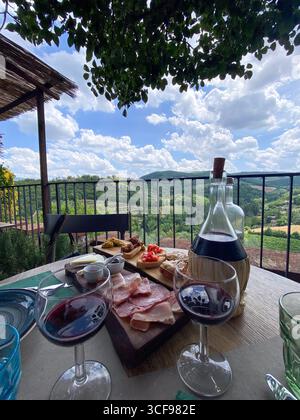 Gläser chianti-Wein und eine Platte mit italienischen Vorspeisen auf einem Tisch mit Blick auf die wunderschöne toskanische Landschaft in montefioralle, italien Stockfoto