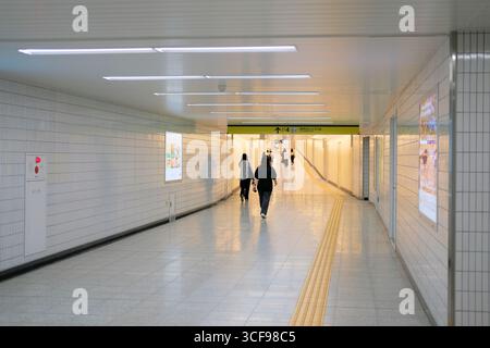Fußgänger in der unterirdischen Passage, die von der U-Bahn-Station Tokyo Roppongi-itchome zum Ausgang 4 in Azabudai Hills führt; Tokio, Japan. Stockfoto