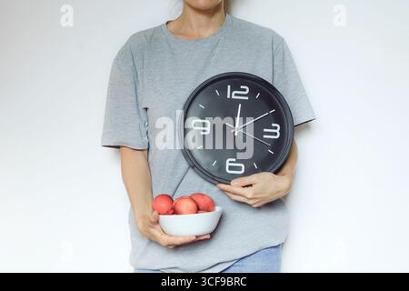 Person mit großer Uhr und Obstschale. Zeitmanagement, Produktivitätseinbußen, ausgewogene Routine, frisches Essen und Einhaltung natürlicher Rhythmen Stockfoto