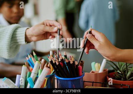Nahaufnahme verschiedener Kinder, die während kreativer Aktivitäten nach Bleistiften greifen Stockfoto