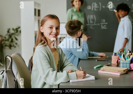 Porträt eines kaukasischen jungen Mädchens, das während des Studiums im Klassenzimmer lächelt Stockfoto