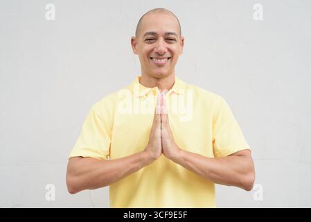 Studio-Porträt eines gutaussehenden, reiferen Italieners mit einem rasierten Kopf, der gelbes Poloshirt trägt, vor einem neutralen, einfarbigen weiß steht Stockfoto