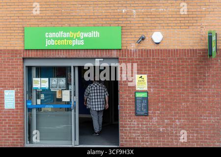 Mann, der in ein Jobcenter in Caerphilly, Wales, Großbritannien geht. Zweisprachiges Schild Canolfan BYD Gwaith auf Walisisch, Job Centre Plus auf Englisch Stockfoto