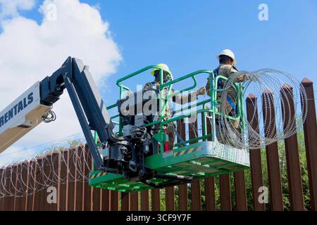 Brownsville, Usa. August 2025. Texas National Guardsmen, die unter der Joint Task Force-Southern Border arbeiten, installieren am 12. August 2025 in der Nähe von Brownsville, Texas, eine Drahtseile entlang der südlichen Grenzmauer zu Mexiko. Die Soldaten wurden von Präsident Trump zur Unterstützung der Operation Lone Star an die Grenze geschickt. Gutschrift: SSgt. Derek Gutierrez/US Air Force Photo/Alamy Live News Stockfoto