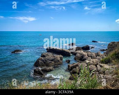 Die felsige Küste von Rocca San Giovanni zeigt das türkisfarbene Wasser der Adria, das an die zerklüftete Landschaft der Abruzzen grenzt, unter hellem Sonnenlicht und enthüllt einen Blick Stockfoto