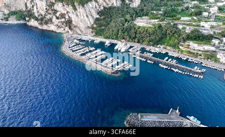 Atemberaubender Blick aus der Luft auf einen ruhigen Yachthafen, eingebettet an den Klippen von Capri an einem sonnigen Nachmittag Stockfoto