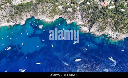 Pulsierendes türkisfarbenes Wasser umgeben zerklüftete Klippen mit Booten unter der Sommersonne und zeigt die atemberaubende Schönheit der Natur Stockfoto