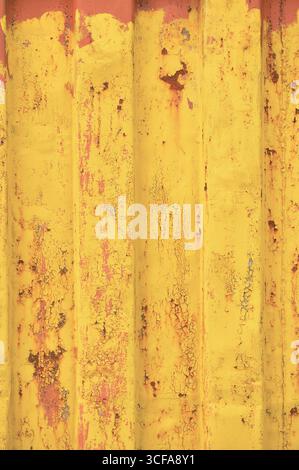 Gelber Grunge Seefracht Container Hintergrund, helles rostiges gewelltes Muster, rote Grundierung Beschichtung, vertikale rostete detaillierte Stahlstruktur, geknackt Stockfoto
