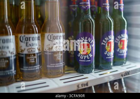 Cremona, Italien 25. Juli 2025 Glasflaschen mit Corona Extra und Tennent's Super Lager stehen in einem gekühlten Vitrinen, bereit zum Kauf. Stockfoto