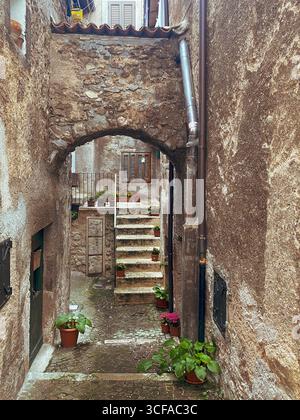 Steinbogen und Treppe mit Topfpflanzen in einer schmalen Gasse von Scanno, Abruzzen, Italien, schaffen eine malerische Szene mit italienischem Charme Stockfoto