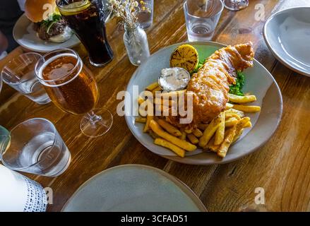 Traditionelle Fish and Chips-Mahlzeit mit matschigen Erbsen, Tatarensauce und Zitronenscheibe – ideal für die Illustration der britischen Küche, Lebensmittelfotografie oder TRA Stockfoto