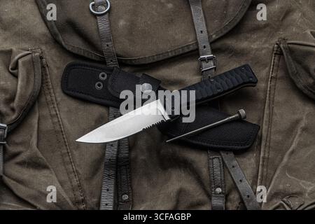 Ein Messer mit fester Klinge, eine Hülle und ein Werkzeug auf einer alten Militärtasche. Stockfoto