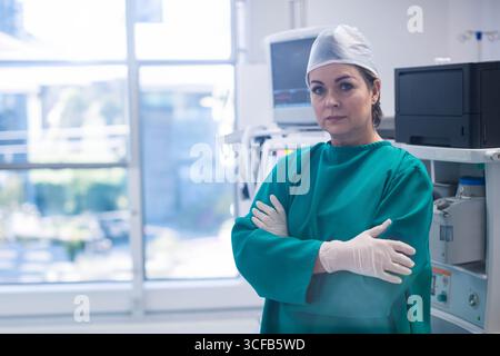 Senior-Chirurgin mit Peelings, die neben dem Anästhesiegerät in der OP-Suite steht, Kopierraum Stockfoto