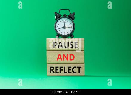 Symbol Pause und Reflexion. Konzeptwörter Pause und Reflexion auf Holzblöcken. Schöner grüner Hintergrund mit Wecker. Business und Pause und Reflec Stockfoto