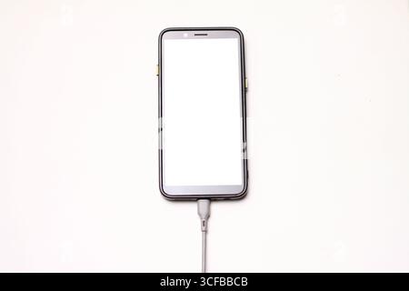 Smartphone mit USB-Kabel verbunden mit weißem Hintergrund. Stockfoto