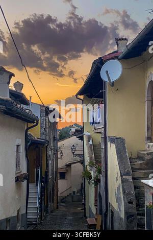Die Wäscherei schwingt sich zwischen verwitterten Steingebäuden, sanftes goldenes Sonnenlicht wirft warme Schatten in die enge italienische Gasse Stockfoto