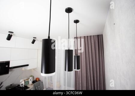 Moderne Pendelleuchten mit schwarzer Diode an einer weißen Stretchdecke, Designer. Stockfoto