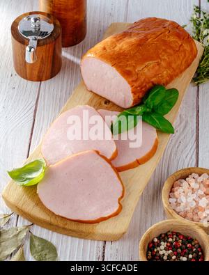 Ein Stück Schinken auf einem Holzbrett mit Kräutern Stockfoto