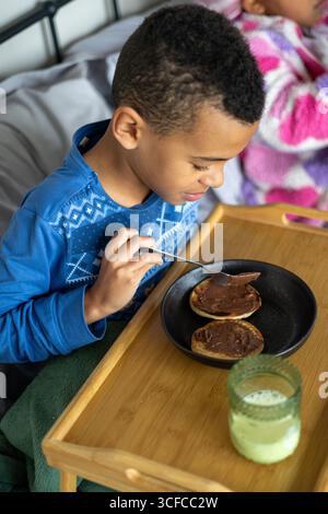 Junge isst im Bett Frühstück Stockfoto