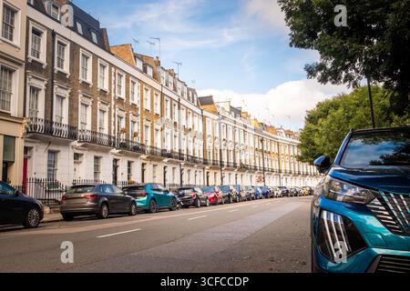 Reihe von Londoner Luxushäusern mit Autos, die auf der Straße in SW1 geparkt sind- Stockfoto