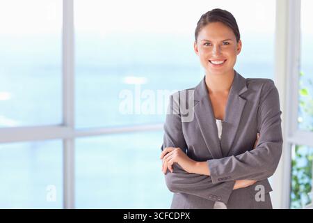 Professionelle Frau, die einen grauen Anzug an den Fenstern und im Topf im Büro, im Kopierraum trägt Stockfoto