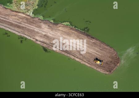 Luftaufnahme des Bulldozers und des Deponiewagens beim Straßenbau in Grünwasser in der Nähe des Bezirks Meden Rudnik, Burgas, Bulgarien Stockfoto