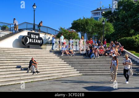 Touristen sitzen auf Stufen zwischen Jackson Square und Washington Artillery Park, New Orleans, Louisiana, USA Stockfoto