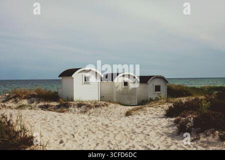 Drei kleine, weiße Strandhütten vor dem Meer bei Höllviken, Falsterbo, Schweden. Stockfoto