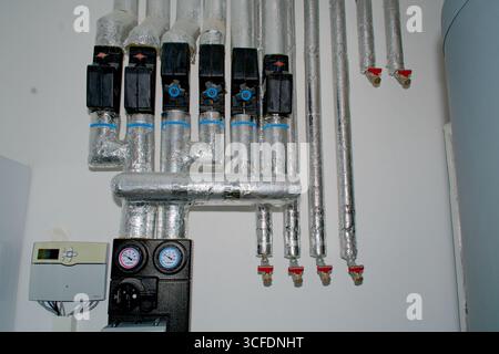 Nahaufnahme eines Heizkreisverteilers (Heizkreisverteiler) als Teil einer Haushaltsheizung mit Rohren und Anschlüssen. Stockfoto