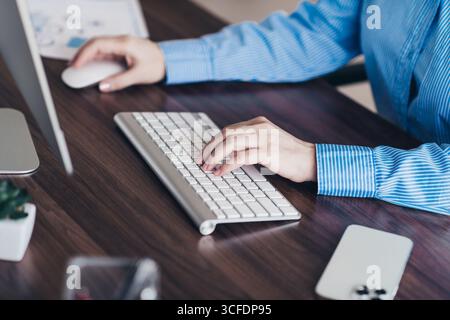 Professionelle Geschäftsfrau, die an einem Computer in einer modernen Büroumgebung arbeitet, auf einer Tastatur schreibt und ihre Produktivität demonstriert Stockfoto