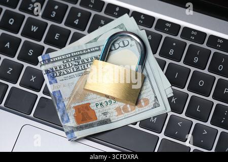 Cyber-Sicherheit. Vorhängeschloss aus Metall und Dollar auf Laptop, Blick von oben Stockfoto