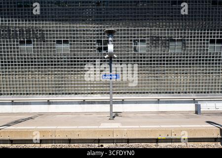 Zürich, Schweiz, 19. August 2025. Zürich HB Hauptbahnhof weiß auf blauem Schild an einem Pfosten in der Nähe eines ebenerdigen Bahnsteigs. Nahaufnahme, Metallzaun bac Stockfoto