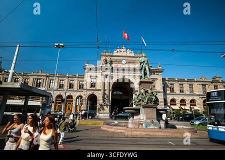 Zürich, Schweiz, 19. August 2025. Die Fassade des Hauptbahnhofs oder des Hauptbahnhofs und die Menschen aus der Sicht der Straßenbahnhaltestelle. Sonniger Sommertag, W Stockfoto
