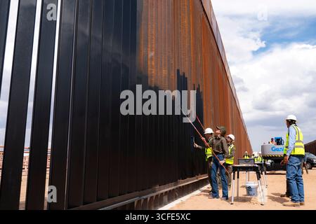 Santa Teresa, Usa. August 2025. Heimatschutzministerin Kristi Noem, links, verwendet eine Malerwalze, um schwarze Farbe auf die US-mexikanische Grenzmauer aufzutragen, auf Befehl von Präsident Donald Trump, 19. August 2025 in Santa Teresa, New Mexico. Quelle: TIA Dufour/CBP Photo/Alamy Live News Stockfoto