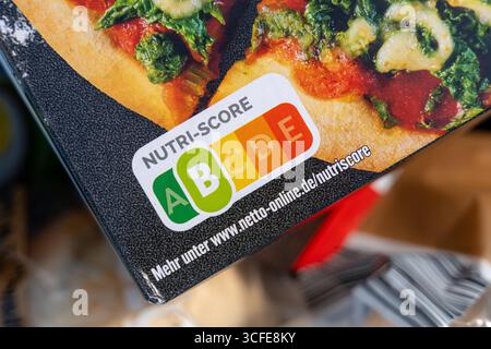 Bayern, Deutschland - 22. August 2025: Nutri-Score-Kennzeichnung auf einer Packung gefrorener Pizza. Die farbige Lebensmittelampel informiert Verbraucher über Nährwerte und hilft ihnen, gesunde oder ungesunde Lebensmittel zu wählen *** Nutri-Score-Kennzeichnung auf einer Packung Tiefkühlpizza. Die farbige Lebensmittelampel informiert Verbraucher über Nährwerte und hilft bei gesunder oder ungesunder Ernährungswahl Stockfoto